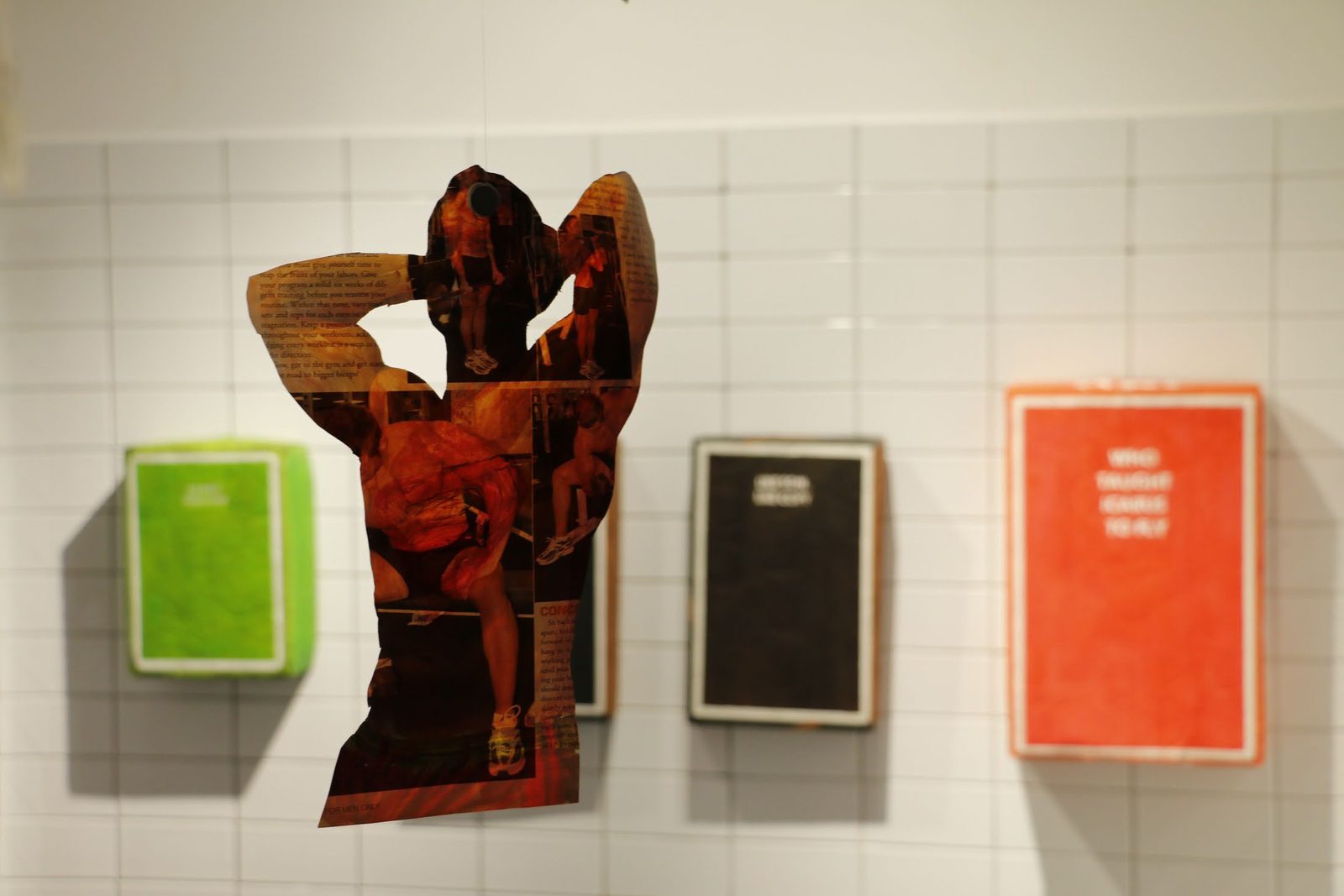 Installation view with cartons and a cutout on a tiled wall